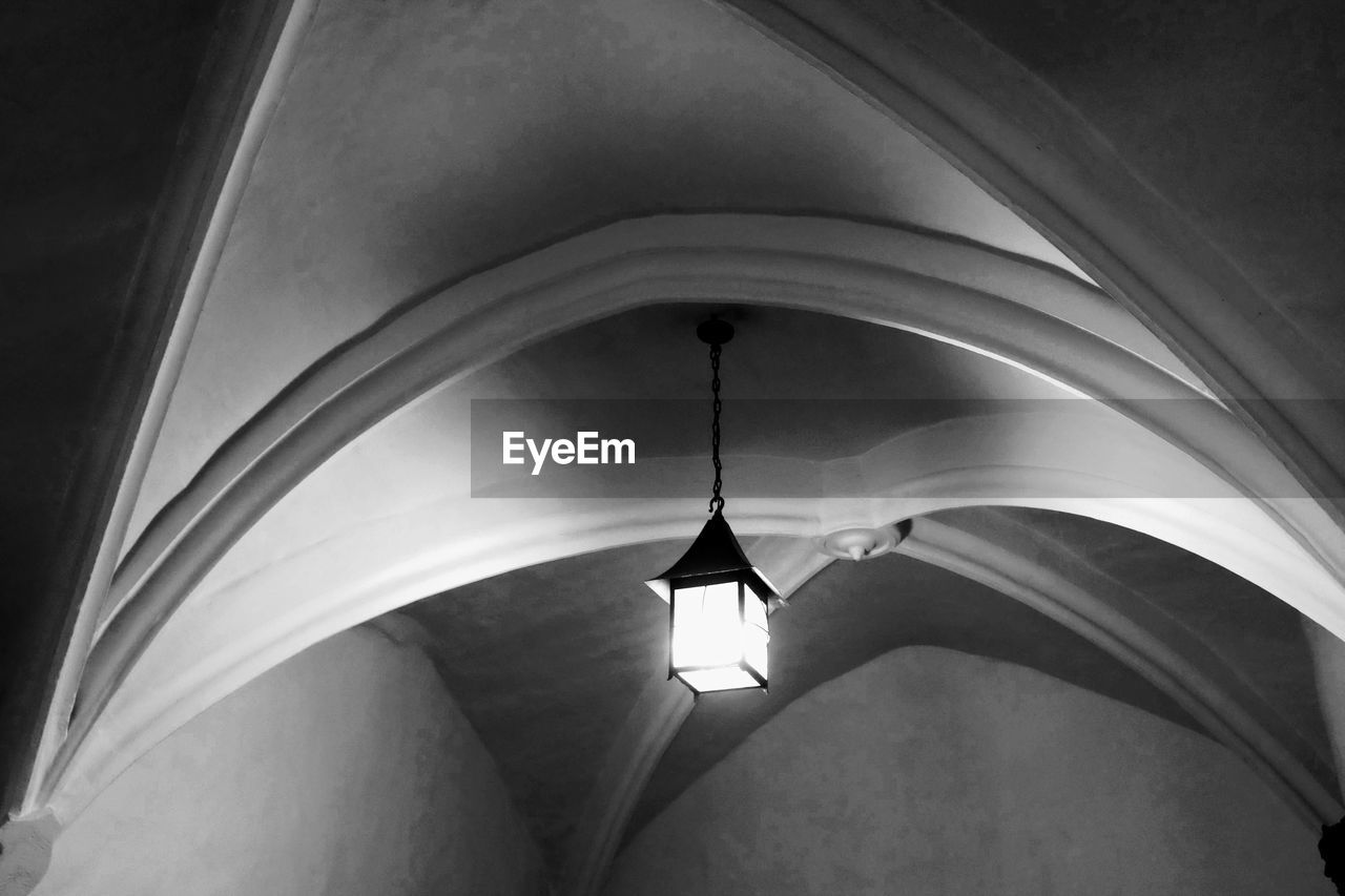 LOW ANGLE VIEW OF ILLUMINATED LIGHT HANGING FROM CEILING IN BUILDING