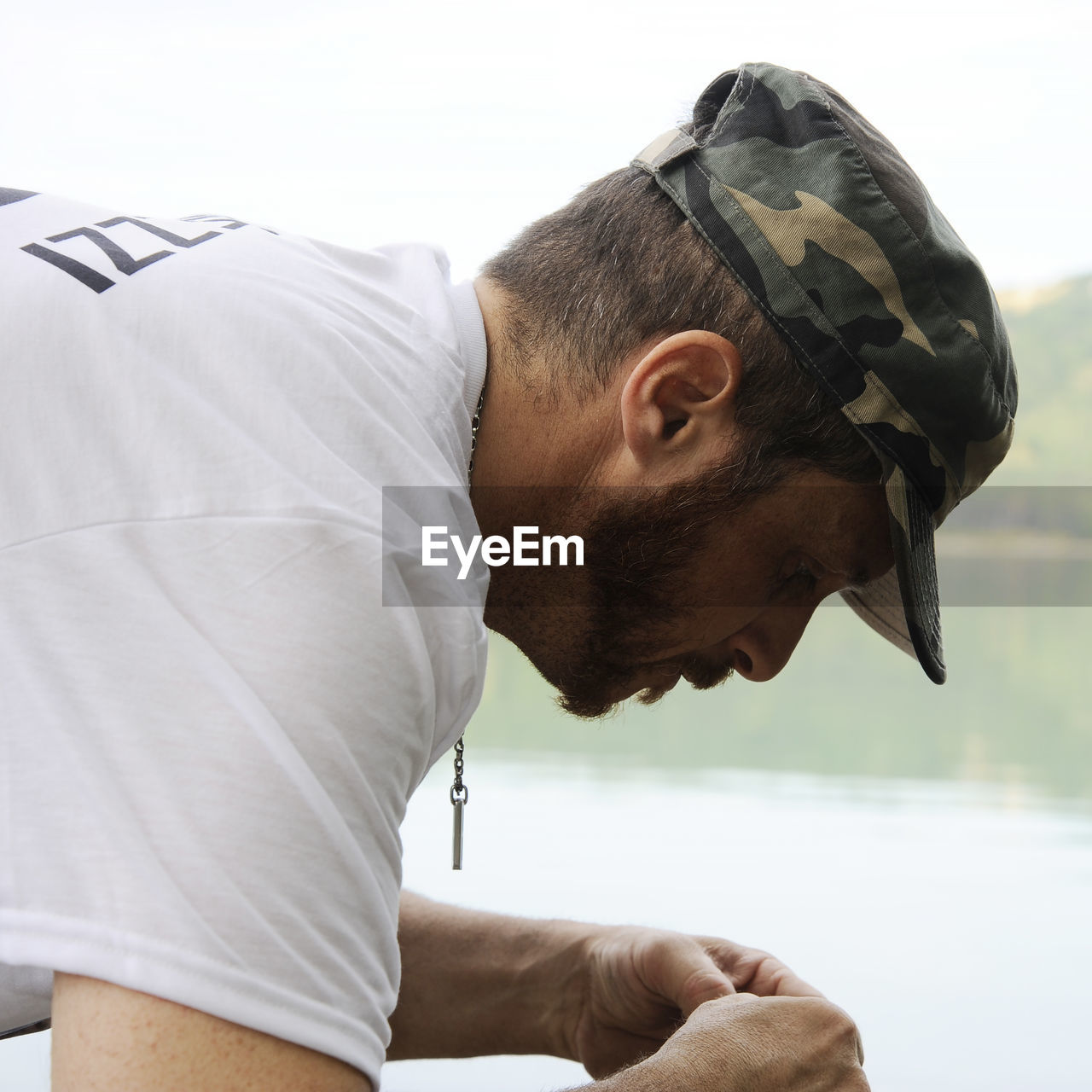 Side view of man wearing cap by lake
