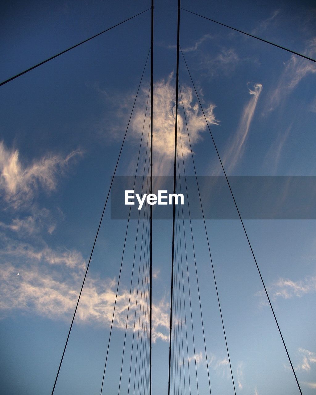 Low angle view of power line against cloudy sky