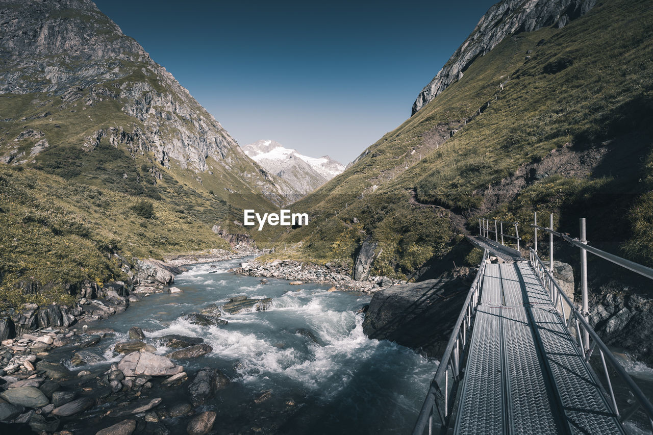 Scenic view of river by mountains against clear sky