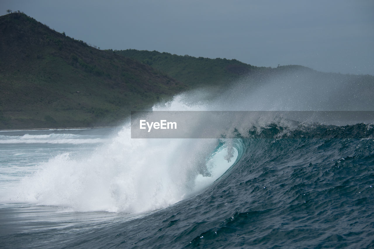VIEW OF WAVES BREAKING AGAINST SEA