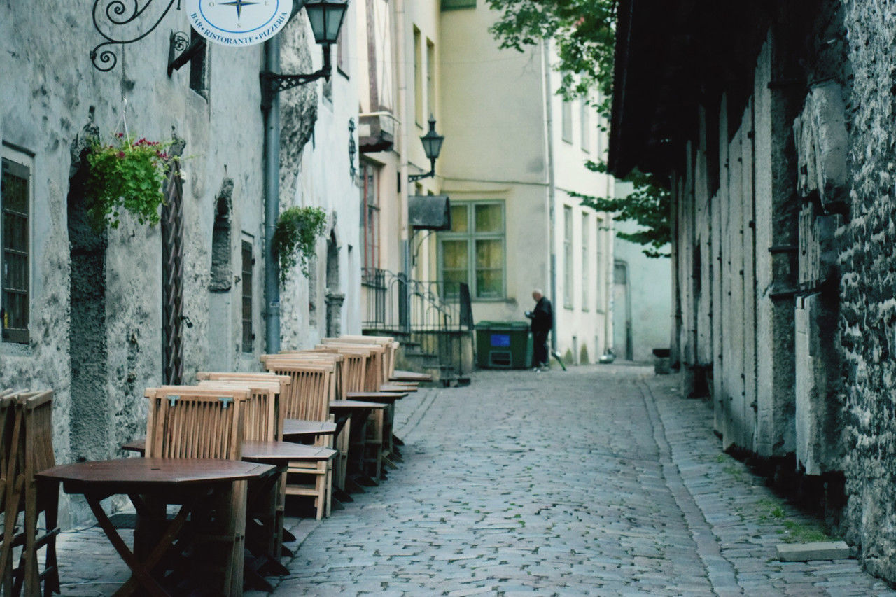 road, street, alley, architecture, built structure, building exterior, town, urban area, seat, building, furniture, infrastructure, city, chair, neighbourhood, table, day, footpath, the way forward, courtyard, cobblestone, outdoors, nature, empty, residential district, cafe