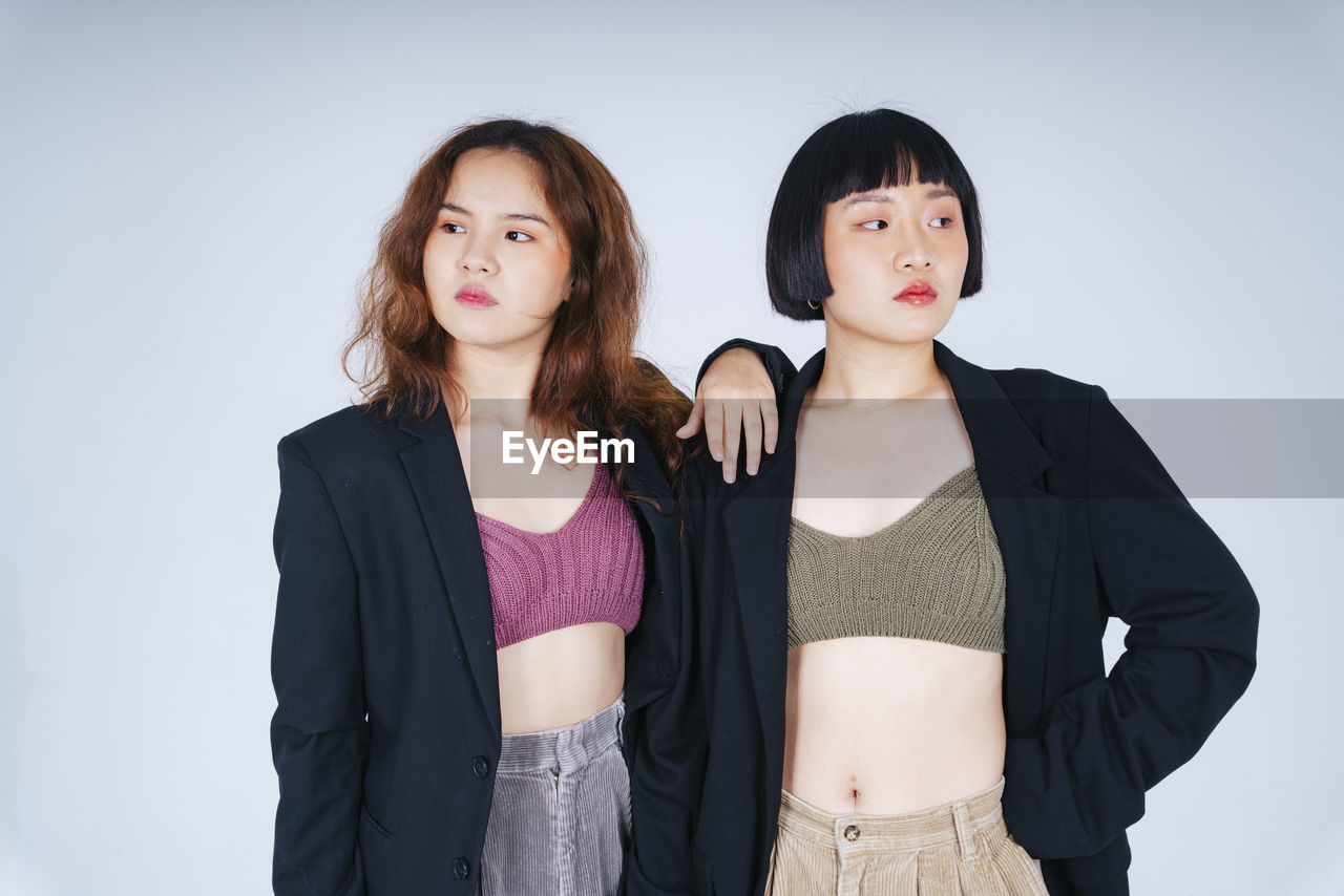 Portrait of lesbian couple wearing blazer against gray background