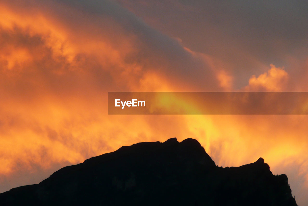 LOW ANGLE VIEW OF SILHOUETTE MOUNTAINS AGAINST DRAMATIC SKY