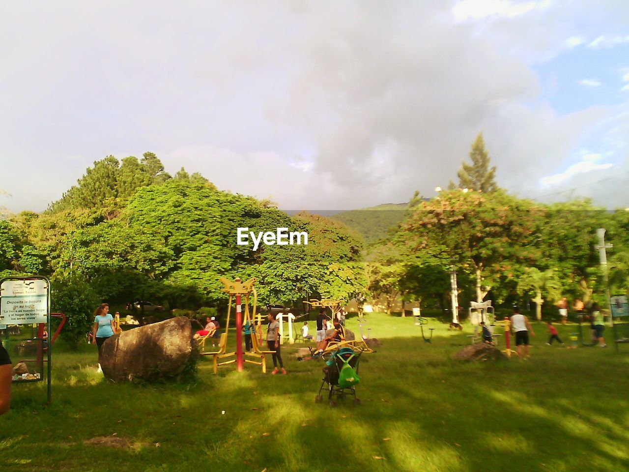 PEOPLE RELAXING ON GRASSY FIELD AGAINST CLOUDY SKY