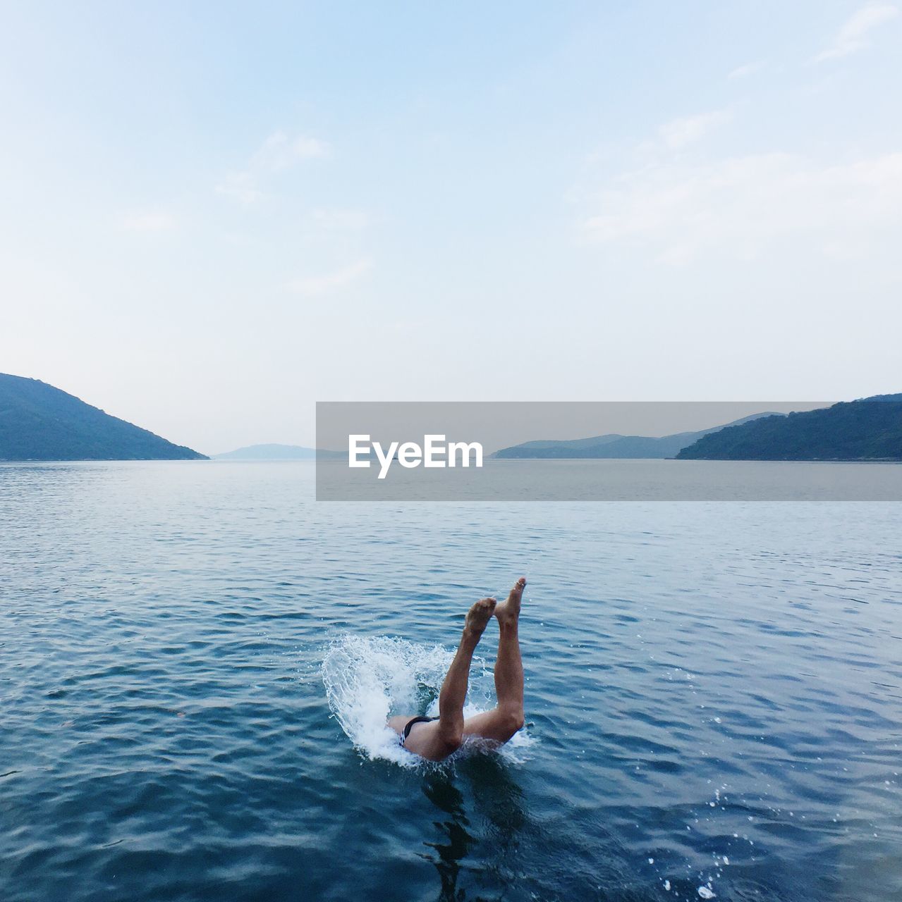 Low section of man diving in water against sky