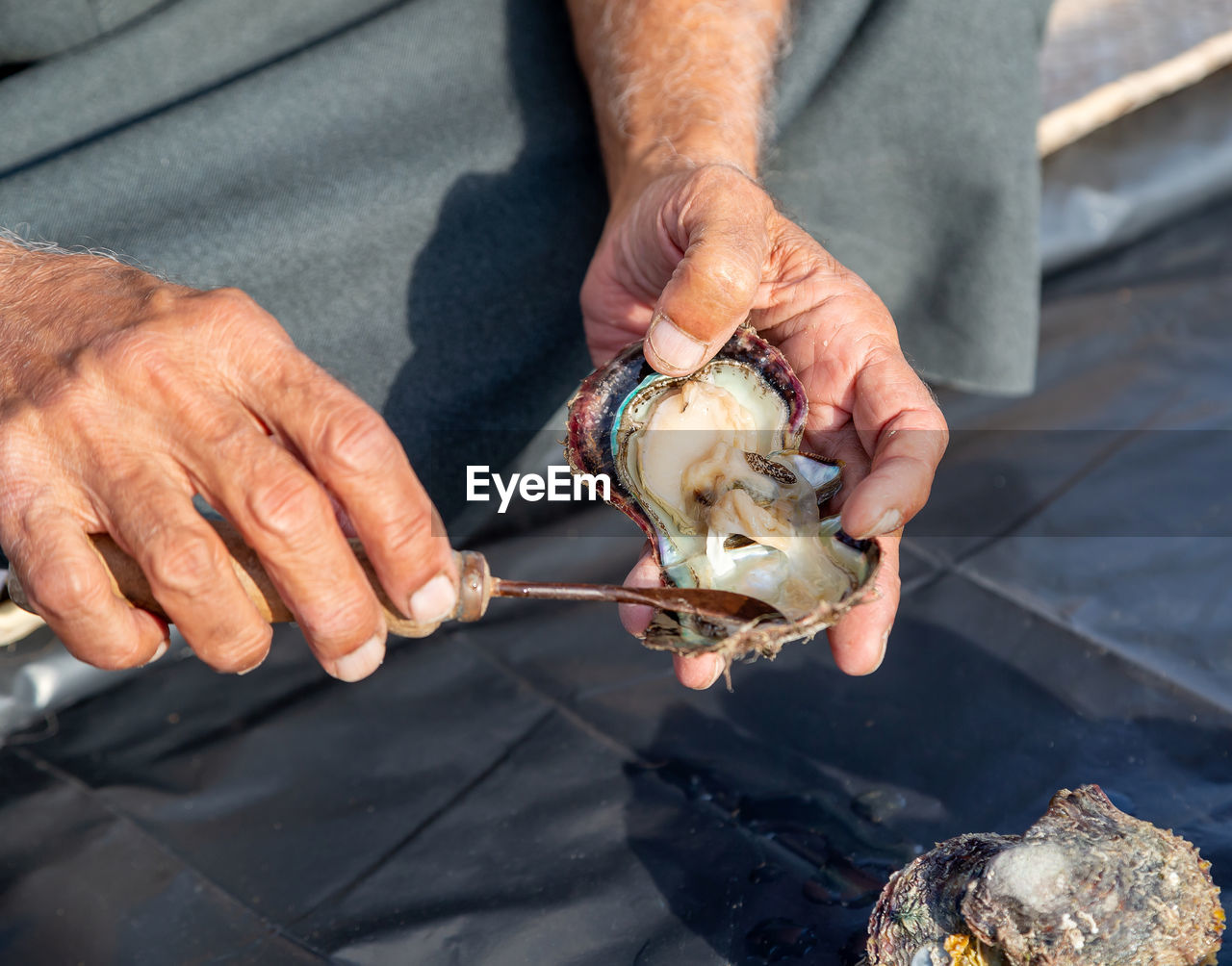 Man opening pearl oyster, hands in frame