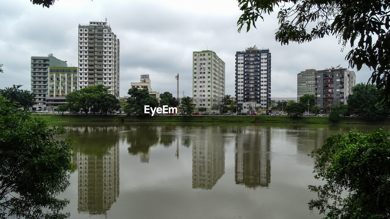 REFLECTION OF BUILDINGS IN LAKE AGAINST SKY