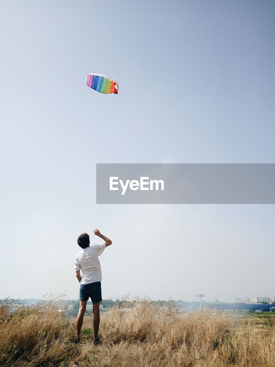 Rear view of man flying kite against clear sky