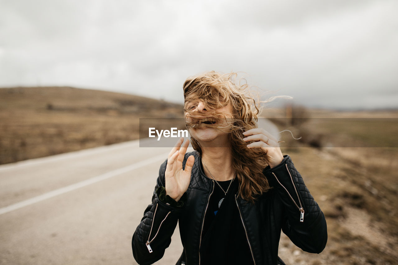 PORTRAIT OF BEAUTIFUL YOUNG WOMAN STANDING ON ROAD