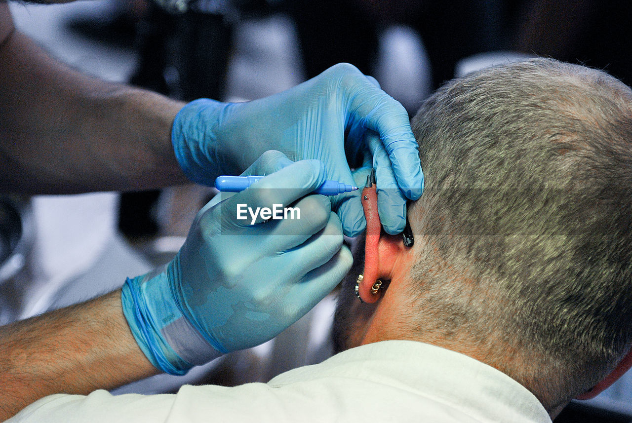 Close-up of artist piercing man ear at studio