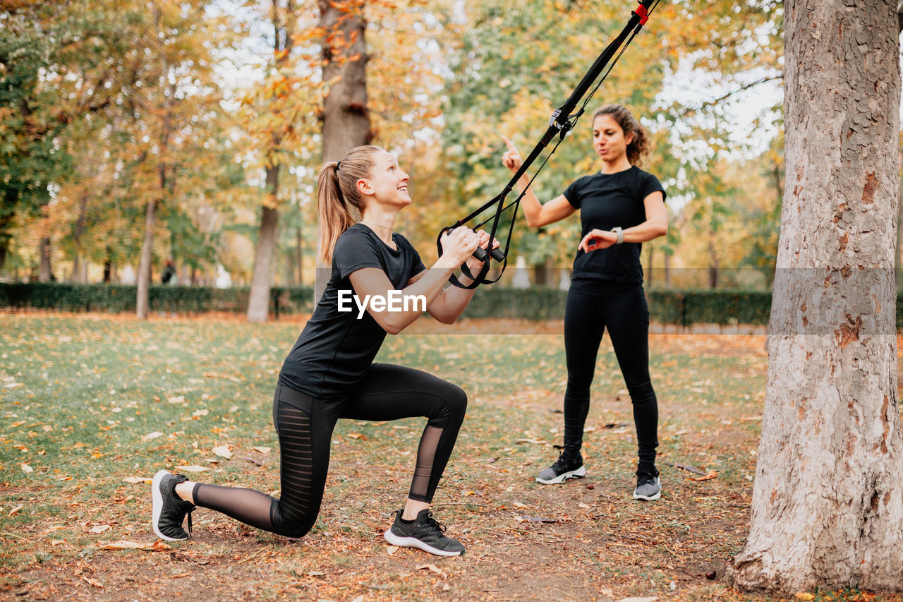 Friends exercising by trees in park during autumn