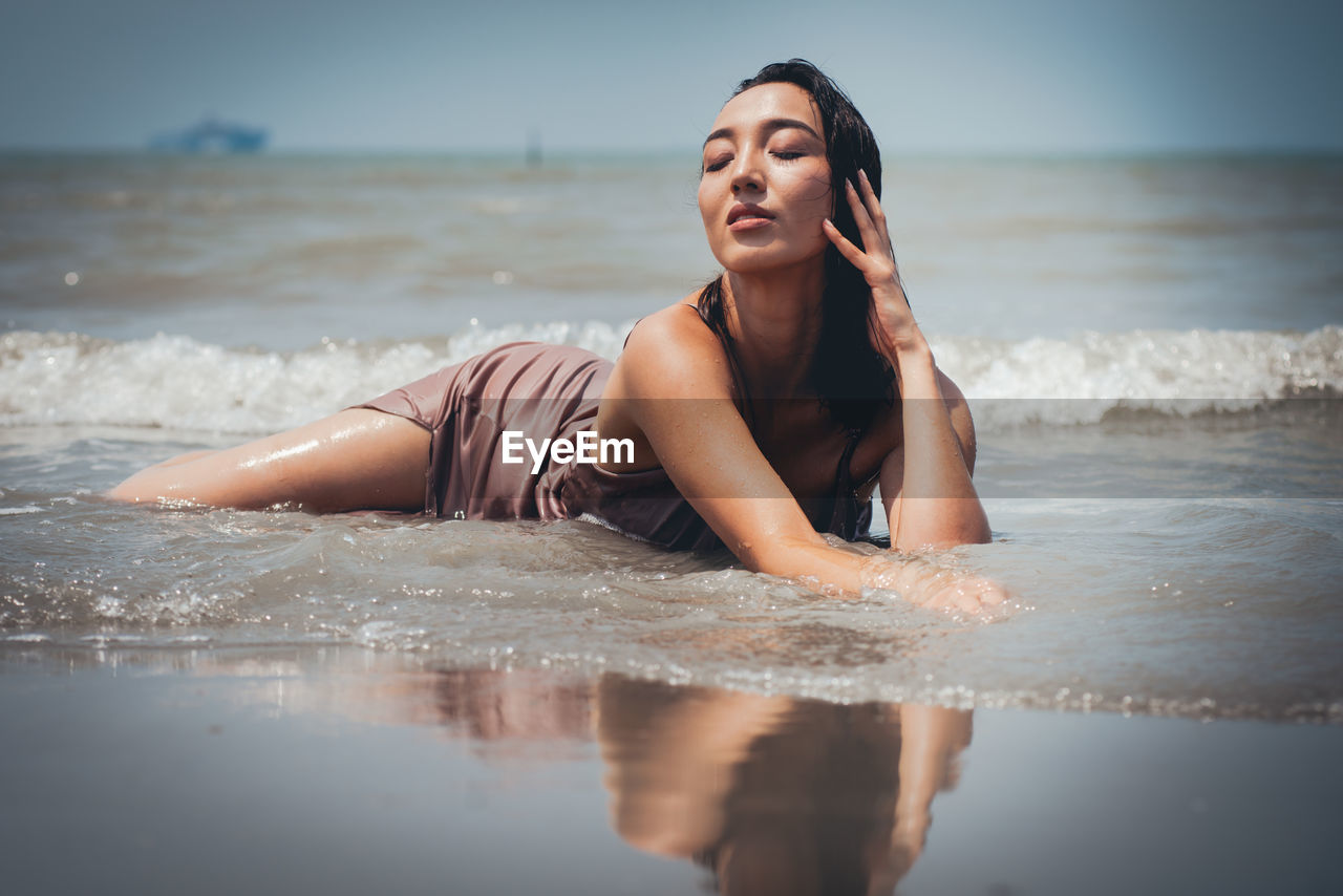 BEAUTIFUL YOUNG WOMAN ON BEACH AGAINST SEA