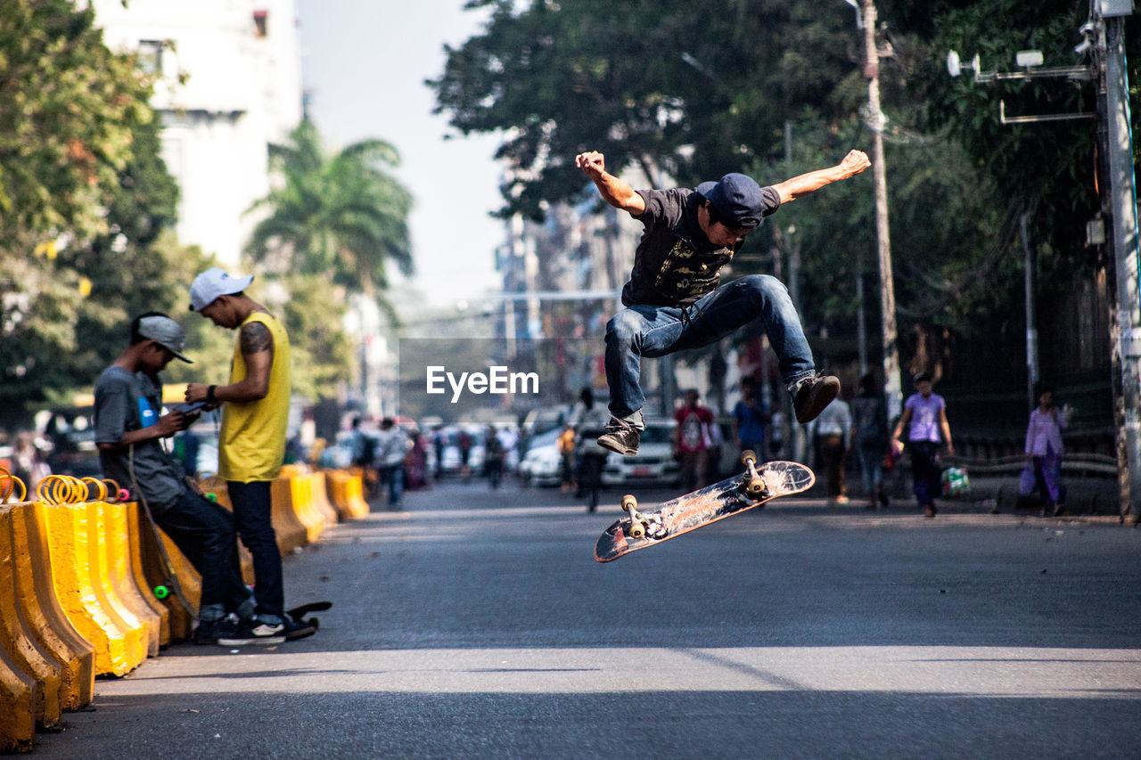 Young man skateboarding on road in city