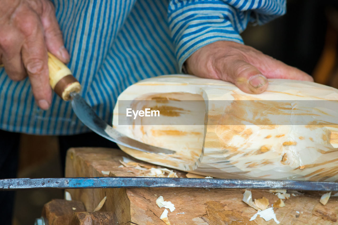 Cropped image of man carving wood at workshop