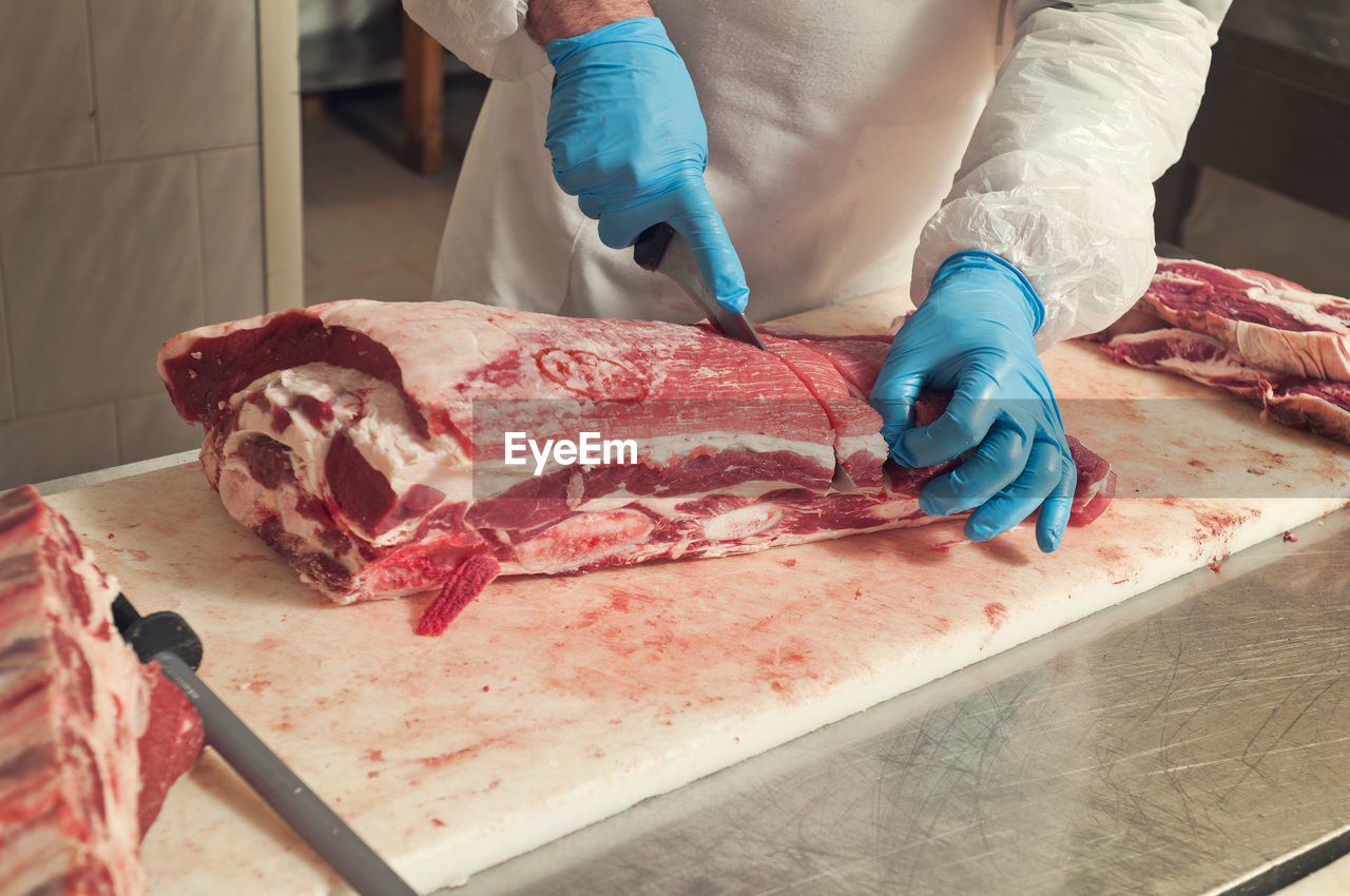 Cropped image of man cutting beef at table