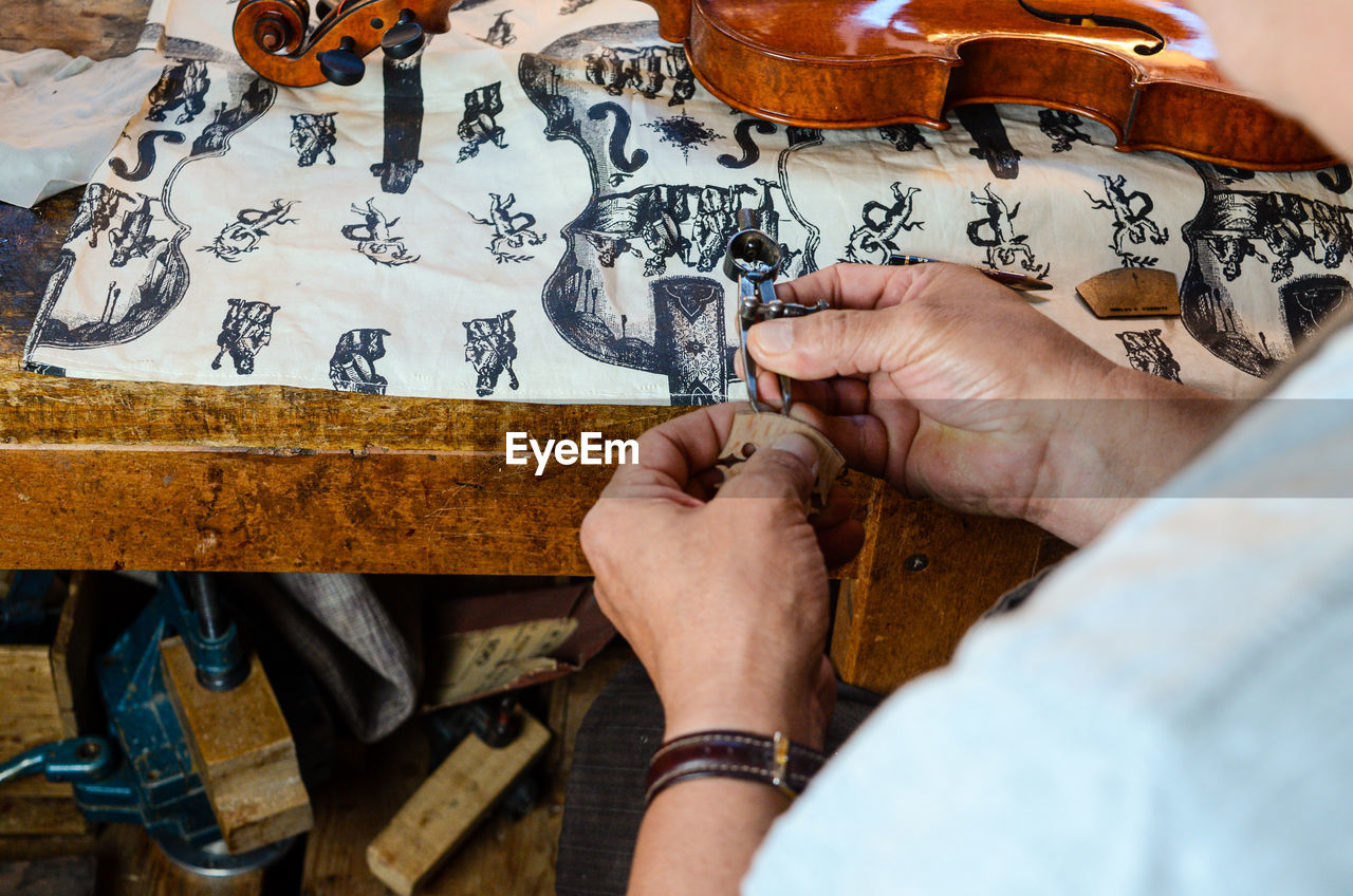 Violin maker luthier changing bridge of a handmade baroque violin