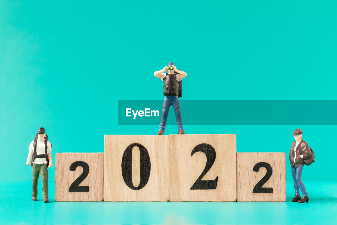 Miniature backpacker and tourist standing on wooden block number 2022 , happy new year concept
