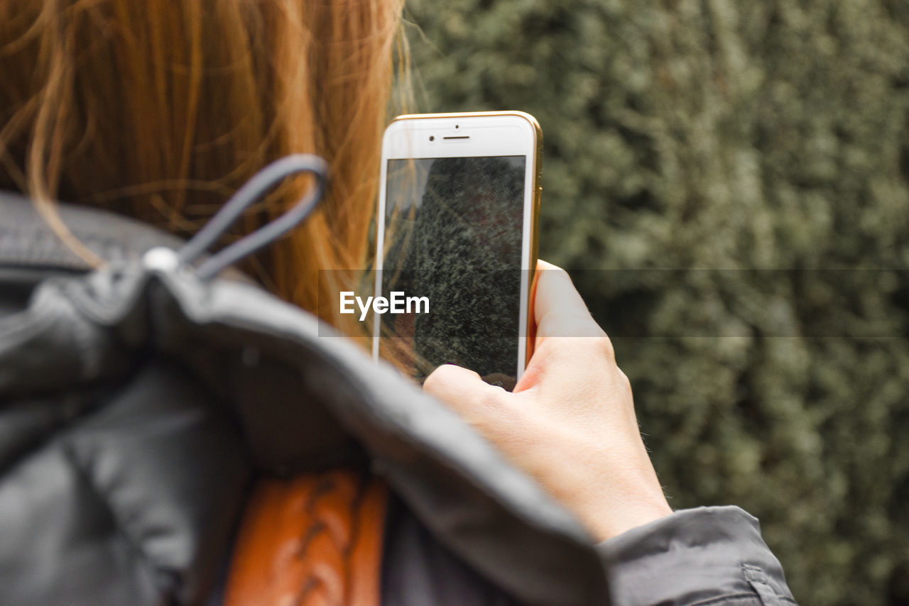 Cropped image of woman photographing plants