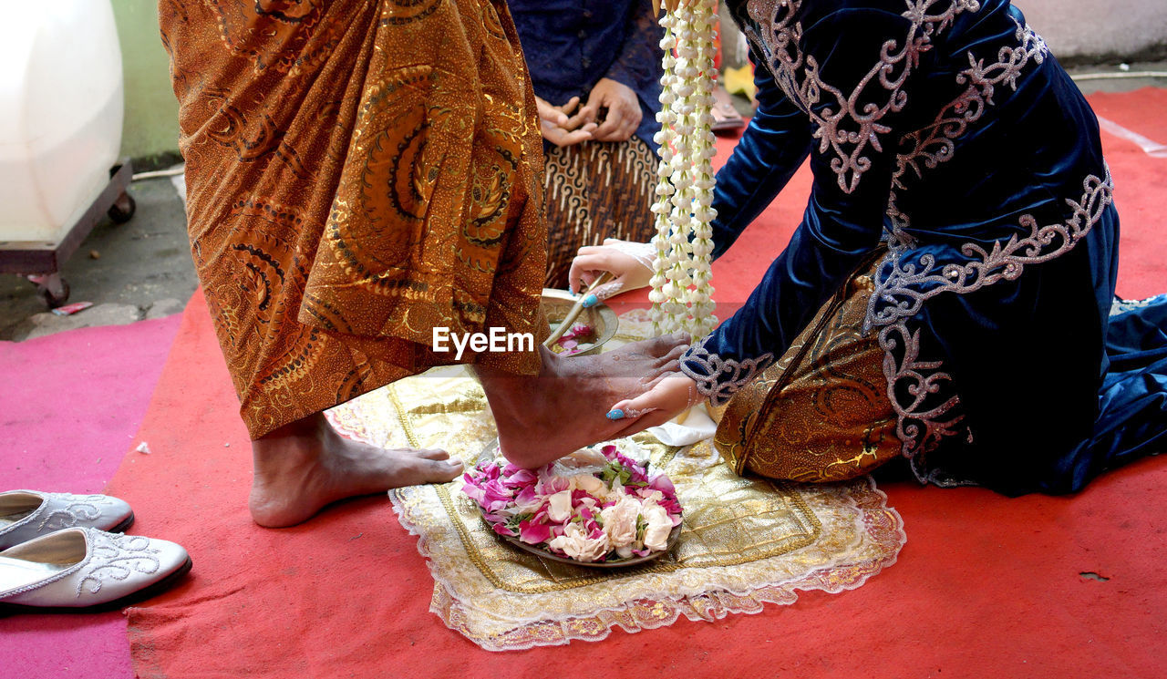 Low section of woman washes groom's feet