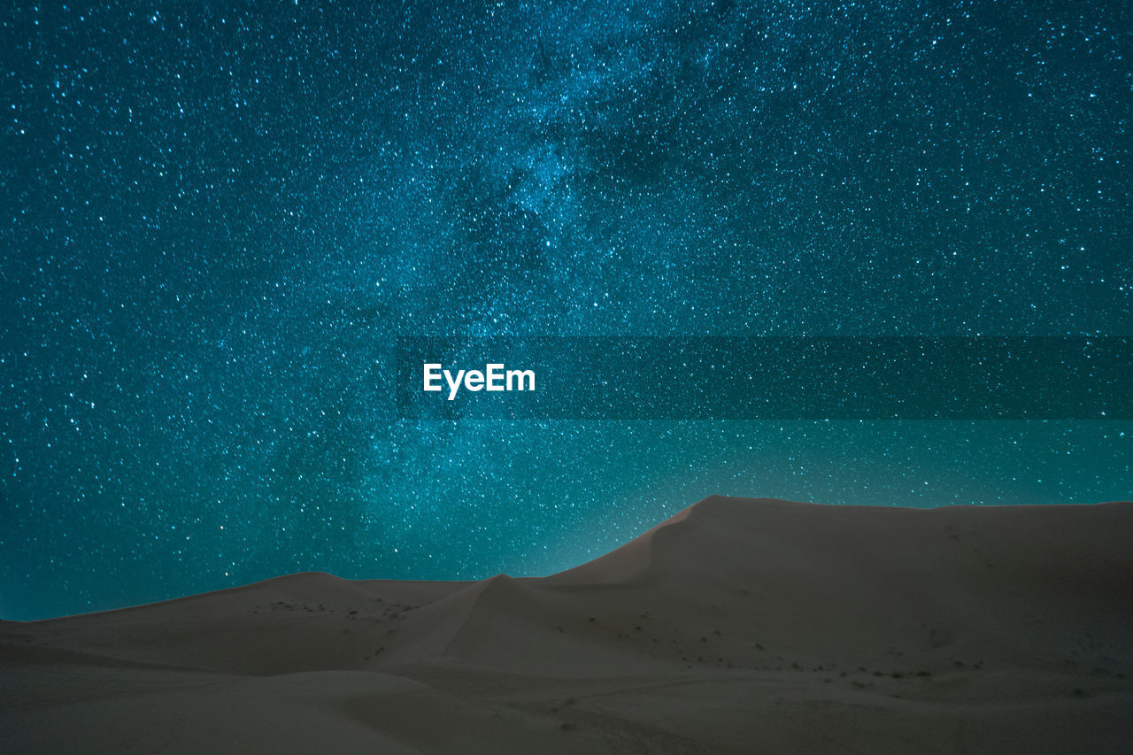 Scenic view of sand dunes in desert against sky at night