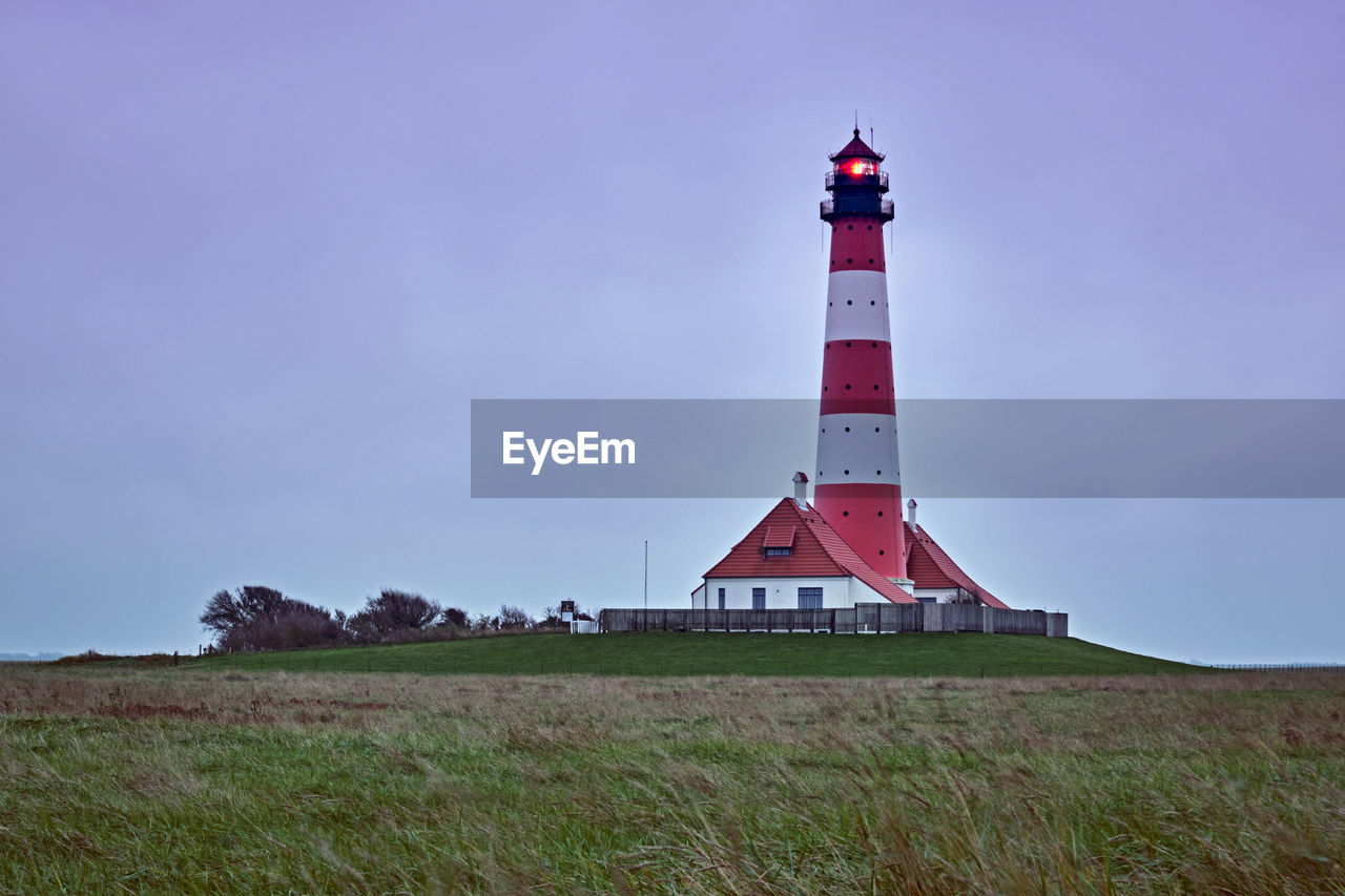 Lighthouse on field against sky