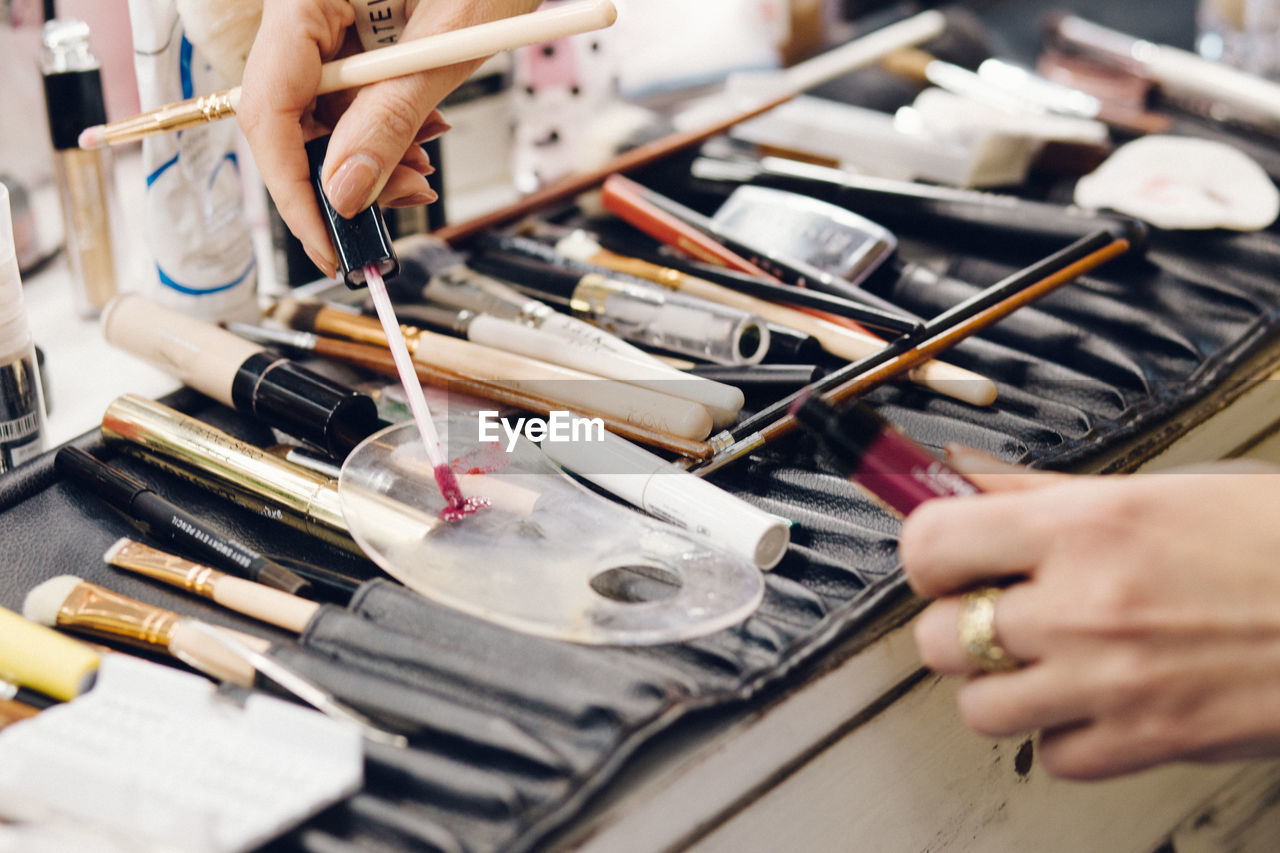 Cropped hand of woman applying beauty product on plastic