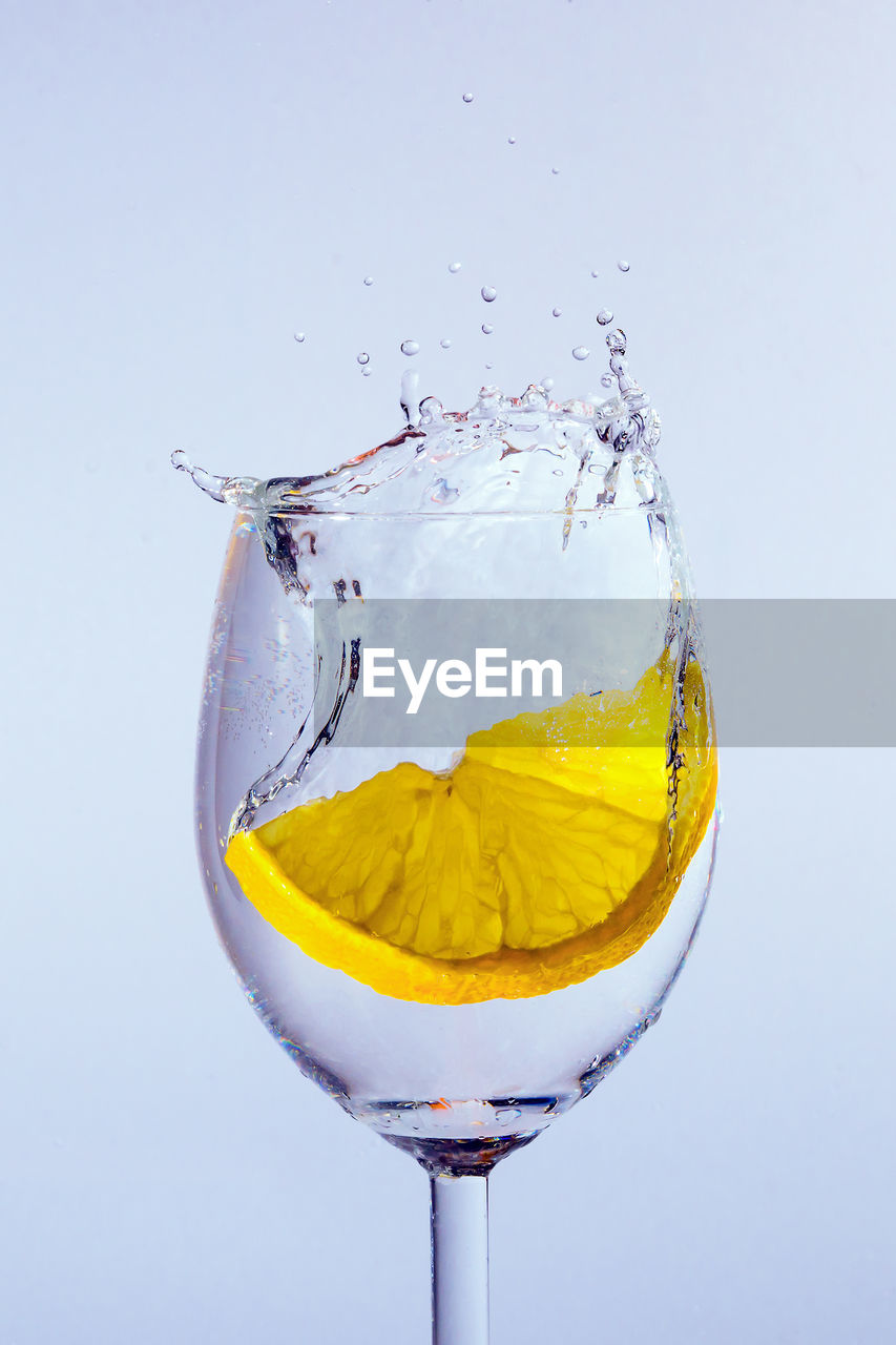 Close-up of lemon splashing water against colored background