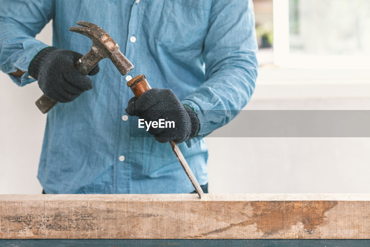 Midsection of man working on wood