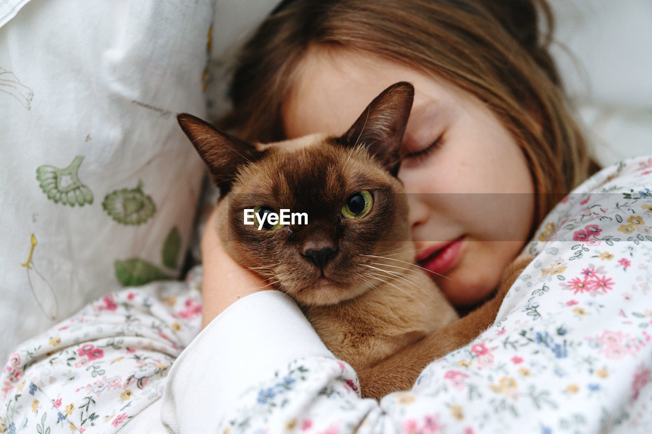 Close-up of sleeping girl with burmese cat