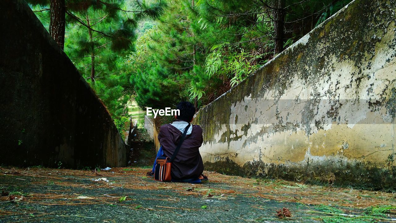 Rear view of man sitting on footpath