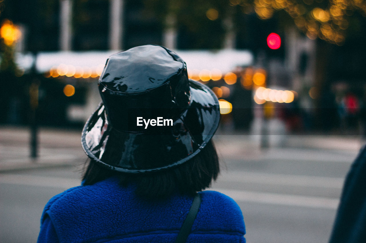 Rear view of woman wearing hat on street in city