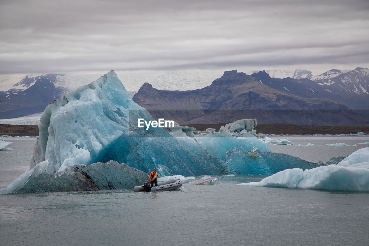 MAN SKIING ON SNOWCAPPED MOUNTAINS AGAINST SKY