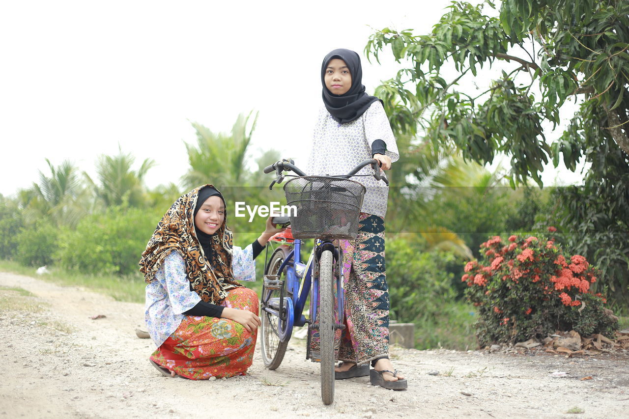 Girls with bicycle on dirt road