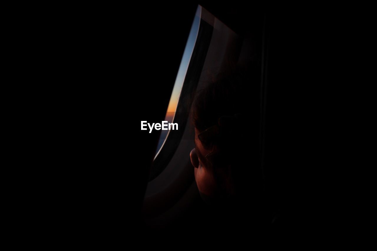 Close-up of girl looking through airplane window