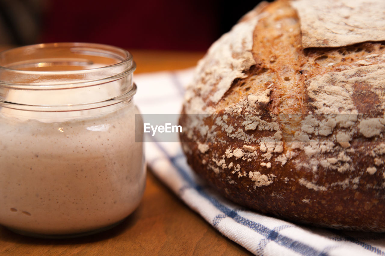 Close-up of sourdough starter and loaf on table