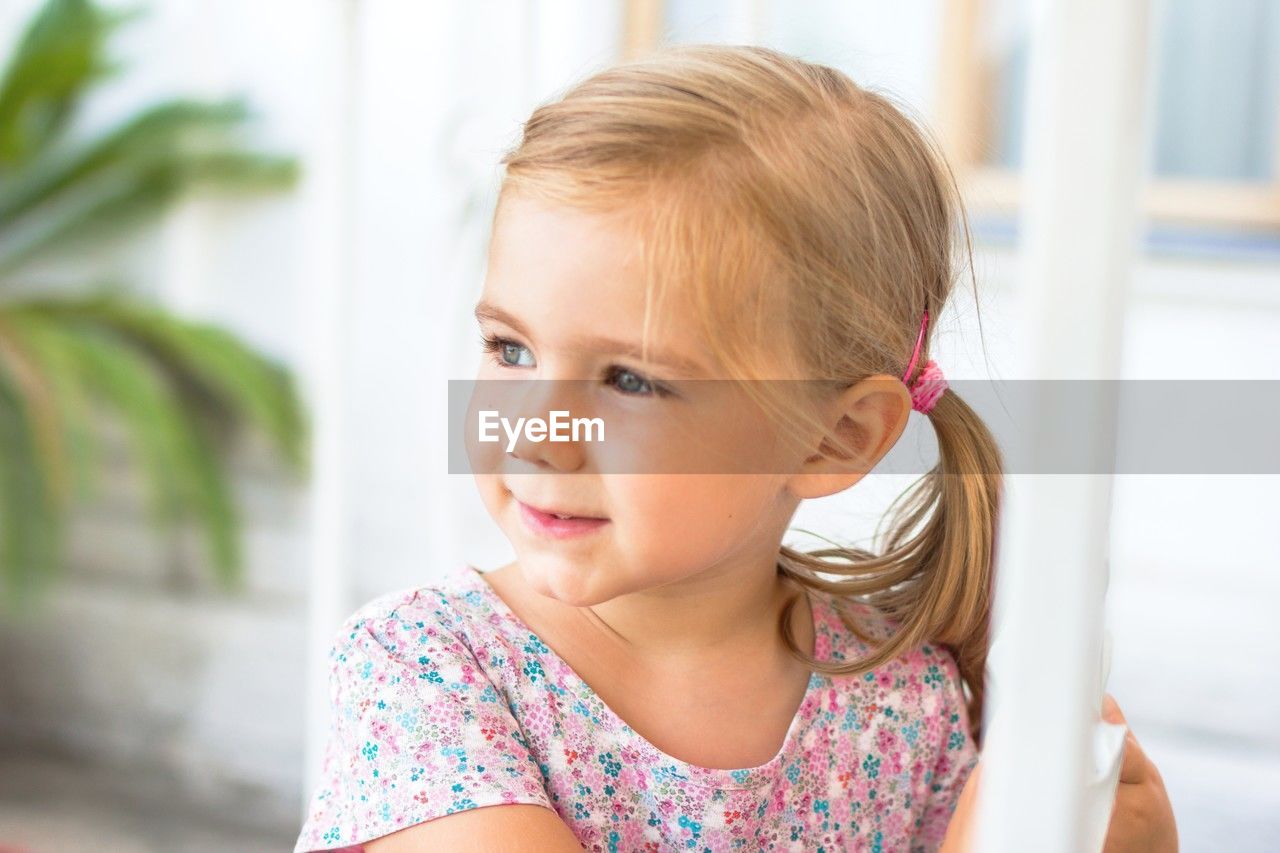 Portrait of a happy blonde girl with a ponytail smiling and making eye contact with the camera.