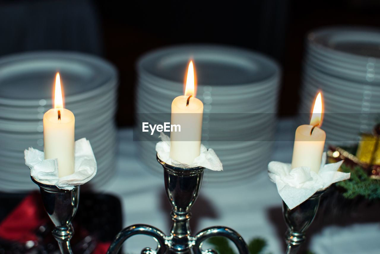 Close-up of illuminated candles on dining table