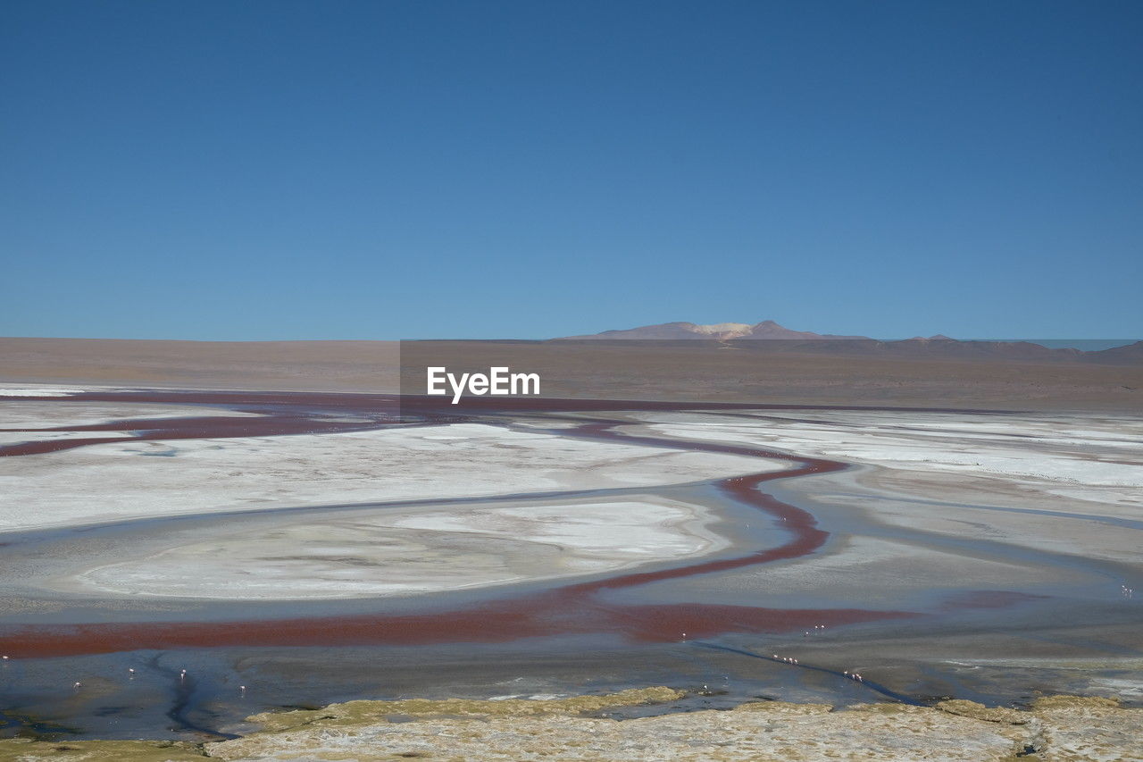landscape, natural environment, environment, scenics - nature, sky, sand, nature, land, blue, clear sky, beauty in nature, desert, no people, tranquility, mountain, non-urban scene, sea, tranquil scene, day, travel destinations, travel, arid climate, plateau, mineral, water, climate, salt flat, geology, horizon, outdoors, remote, physical geography, sunny, copy space, tourism, salt - mineral, plain, coast, extreme terrain