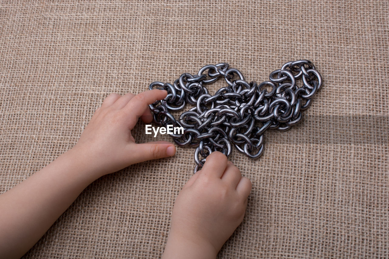 Cropped hands with chain on table