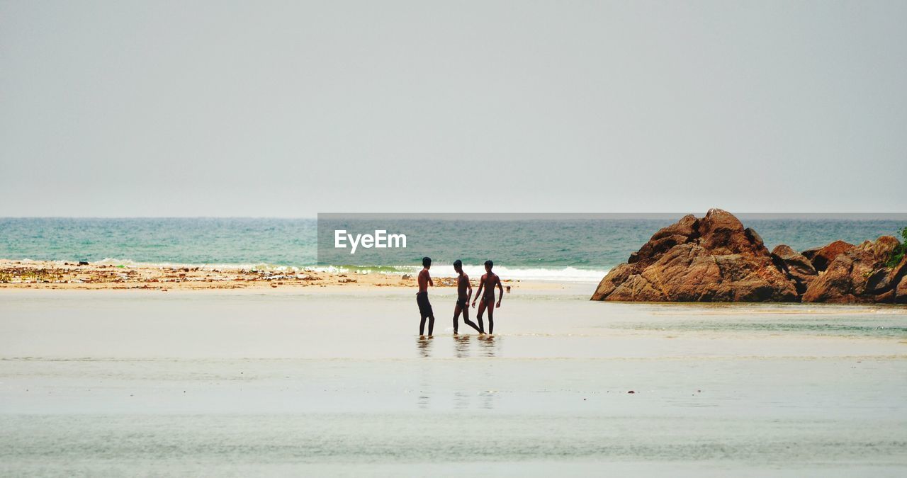 People on beach against clear sky