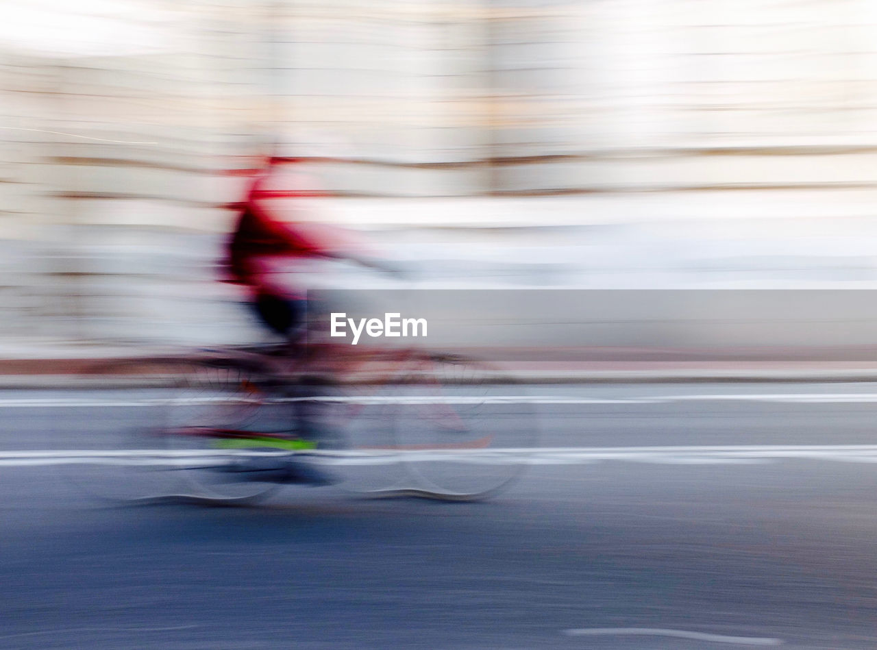 Blurred motion of person riding bicycle on road