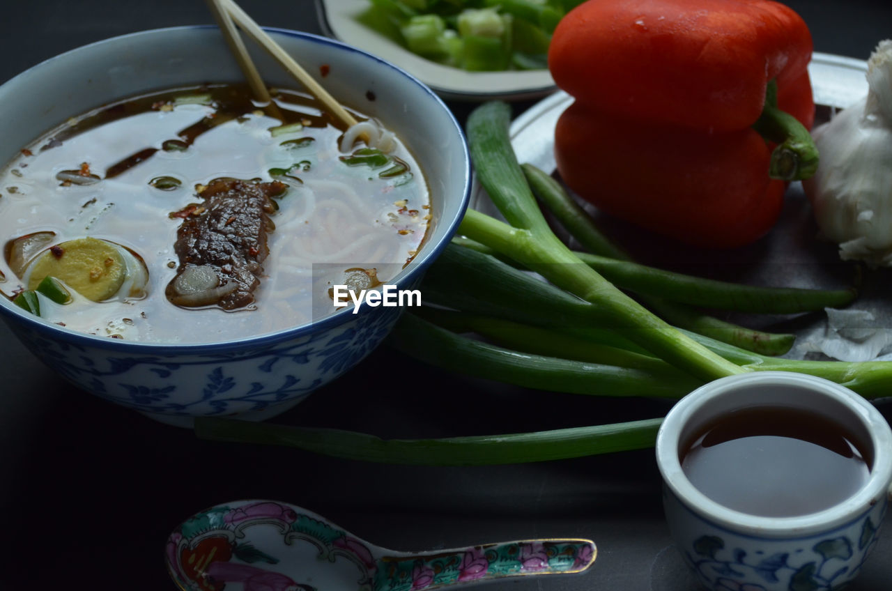 Asian inspired beef noodle soup with green onions, tea