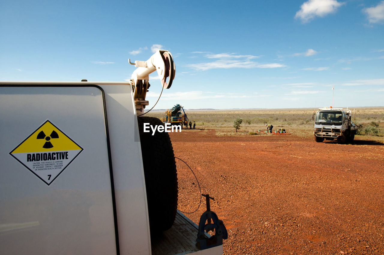 Close-up of commercial land vehicles on field against sky