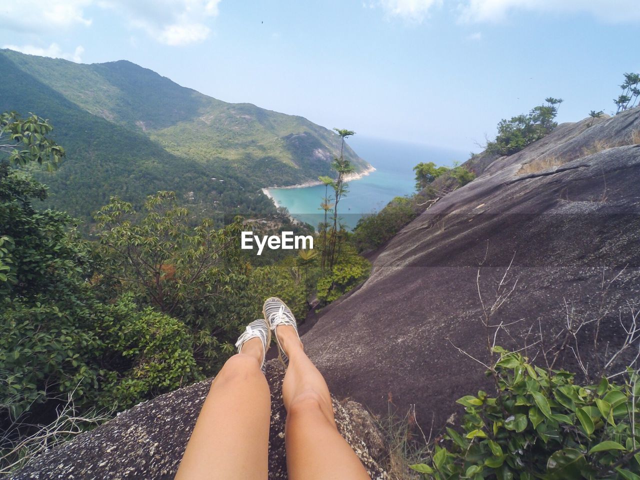 Low section of woman on mountain against sky