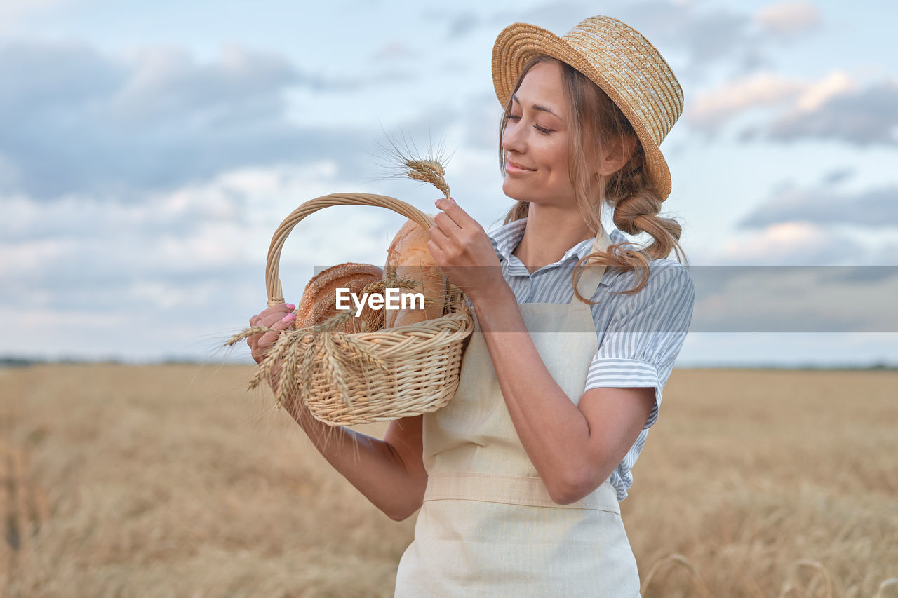 MIDSECTION OF WOMAN WEARING HAT STANDING IN BASKET