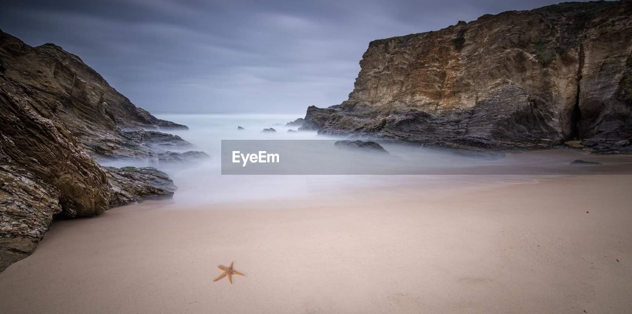 Scenic view of rocks on beach against sky