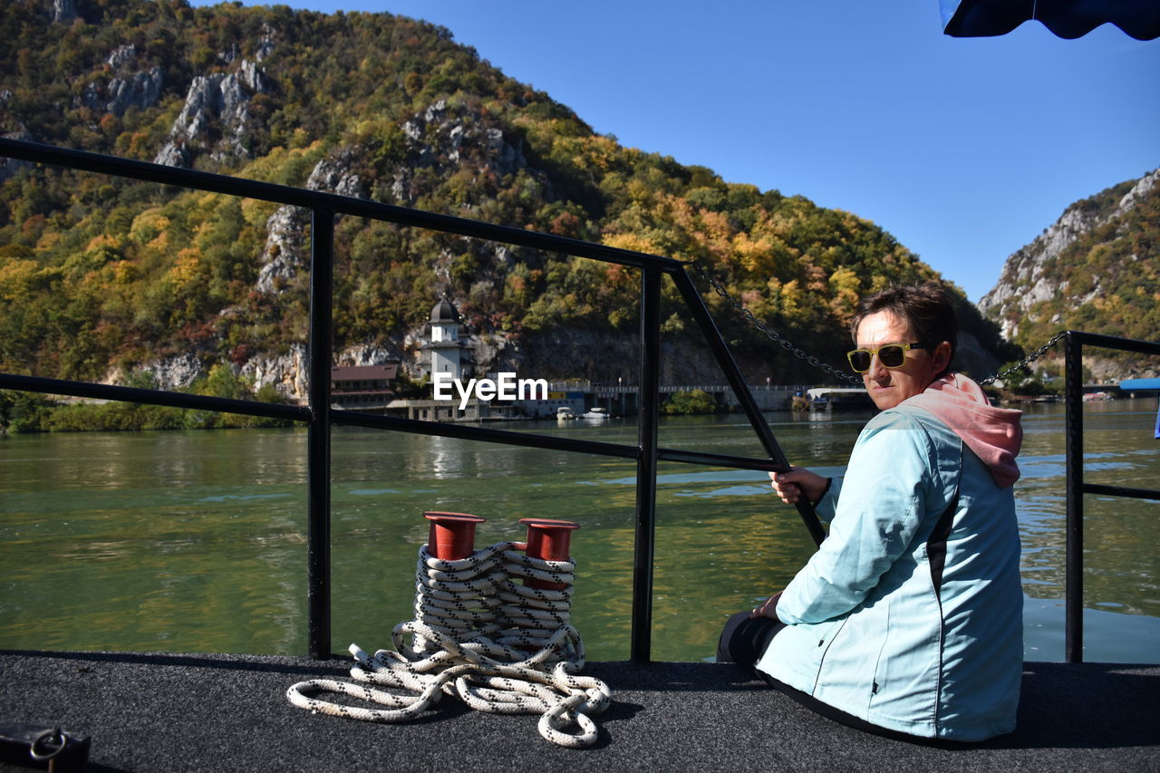 Portrait of woman sitting on pier over lake