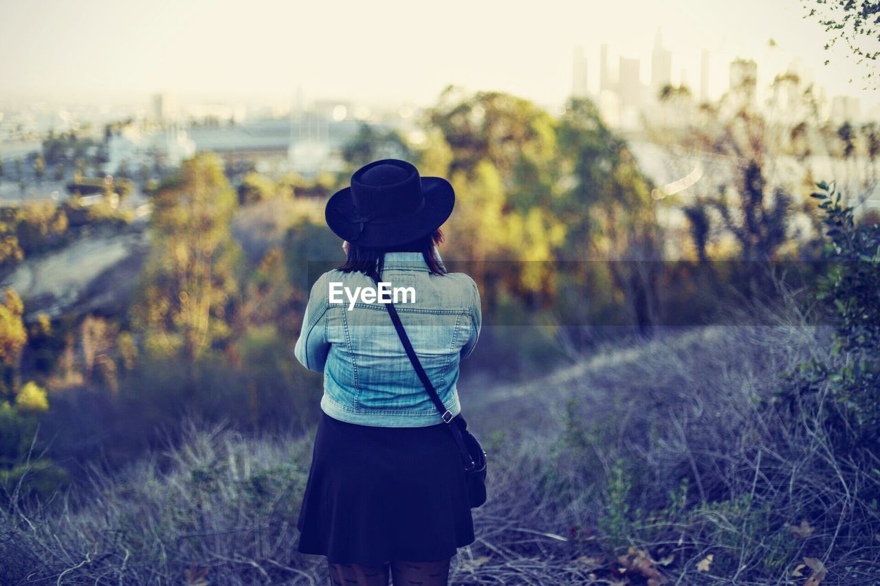 Rear view of woman standing amidst grass