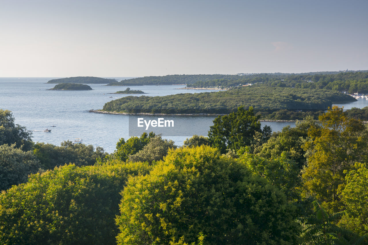 Scenic view of sea with smail island against clear sky